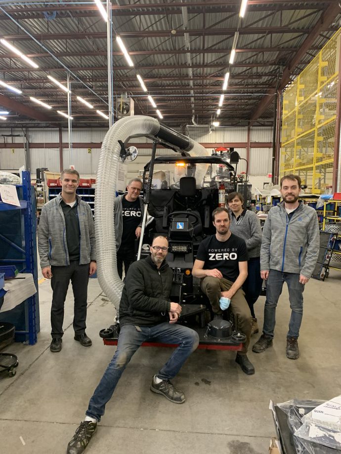 A group of employees from Exprolink's engineering team pose around an electric Madvac vehicle wearing Zero electric battery company t-shirts.