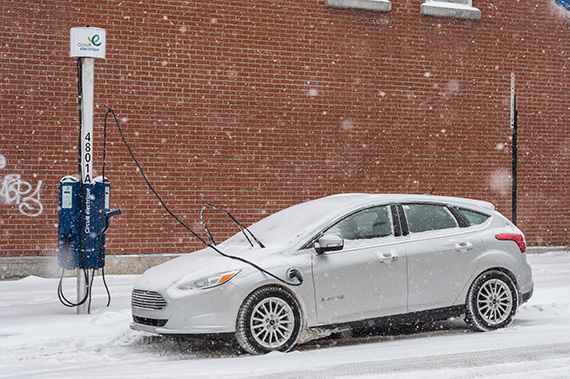 An electric car connected to a charging station during a snowstorm