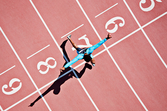 A runner reaches the finish line on an athletics track.