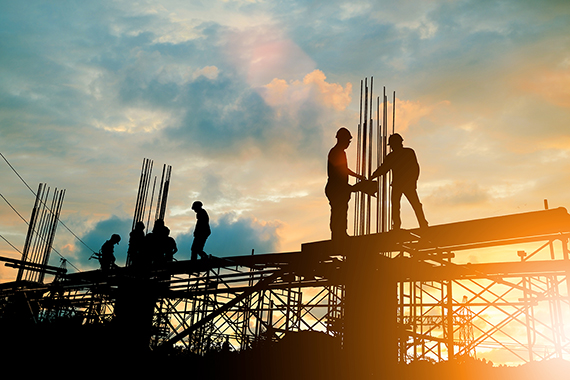 Silhouette of an engineer and a construction crew working on a site with a sunset background