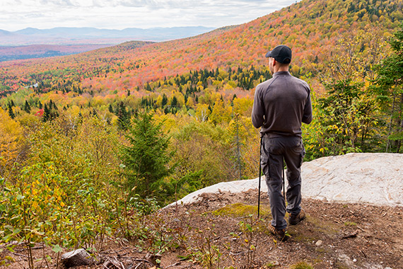 A walker admiring the fall scenery on a mountain trail.