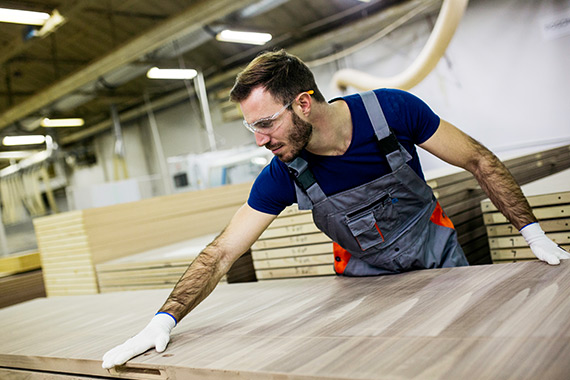 A factory worker handling a wooden panel.