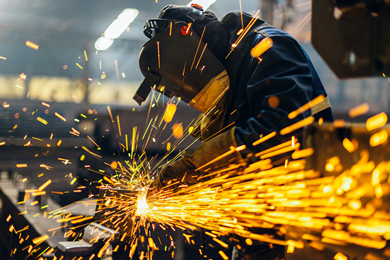 A welder working metal in a factory.