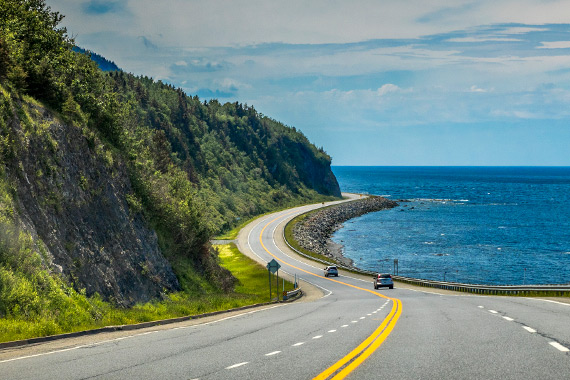 A coastal road alongside a mountain on a beautiful sunny day.