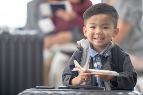 A little boy of about three years old holds a toy airplane in his hands while waiting to fly.