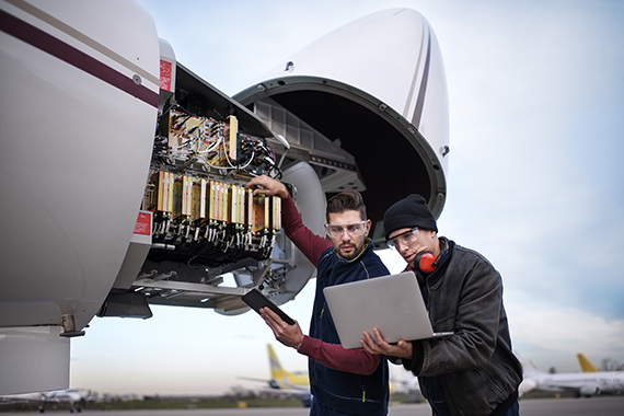 Two mechanics are repairing the engine of a plane